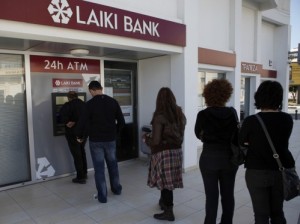 People queue to use an ATM outside of a Laiki Bank branch in Larnaca, Cyprus, on Saturday. Many rushed to cooperative banks after learning that the terms of a bailout deal with international lenders includes a one-time levy on bank deposits.