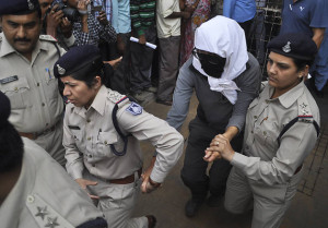 A brutálisan megerőszakolt turistanőt a saját érdekében arcát betakarva kísérik a rendőrök
