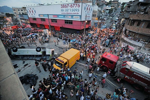 People surround a bus which fell from a