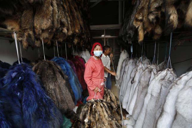 A worker hangs bundles of mink fur inside a store at a fur market in Chongfu township