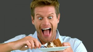 stock-footage-attractive-man-about-to-eat-a-cake-on-grey-screen-in-slow-motion