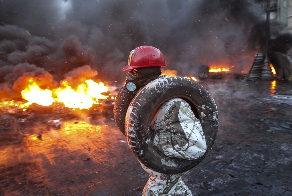 A pro-European integration protester carries tyres for burning at the site of clashes with riot police in Kiev