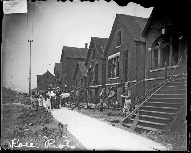 Soldiers with rifles stand guard at vandalized houses, Chicago, Illinois, July, 1919