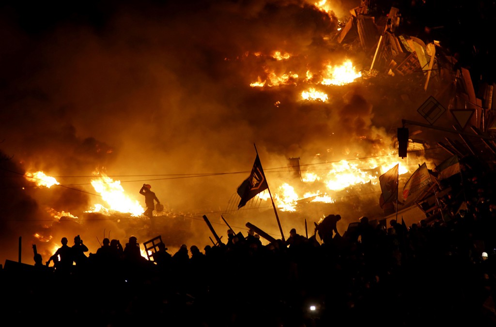Anti-government protesters stand behind burning barricades in Kiev's Independence Square