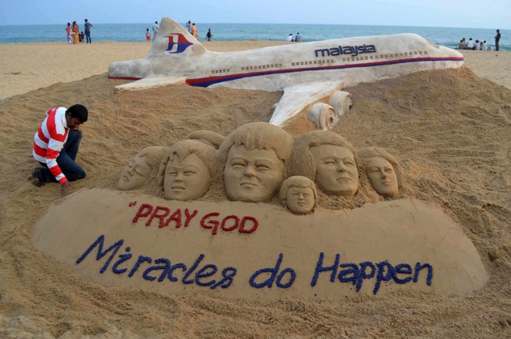 Indian sand artist Patnaik applies final touches to a sand art sculpture he created wishing for the well being of the passengers of Malaysian Airlines flight MH370, on beach in Puri, in the eastern Indian state of Odisha