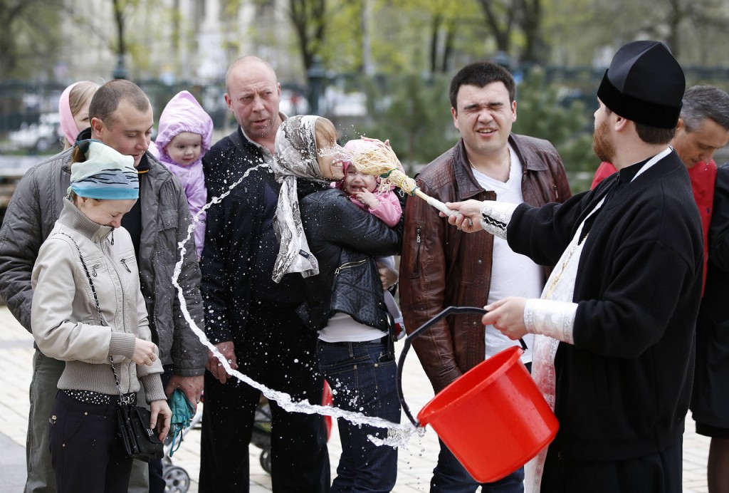 Ukrainian Orthodox priest sprinkles holy water on believers during Easter in Donetsk