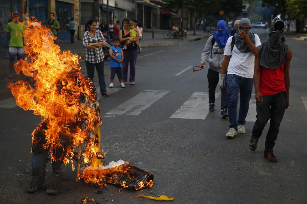 Anti-government protesters walks past a burning effigy depicting Chacao's mayor Ramon Muchacho in Caracas