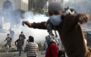 Protesters opposing Egyptian President Mohamed Mursi flee from tear gas fired by riot police during clashes along Qasr Al Nil bridge , which leads to Tahrir Square in Cairo
