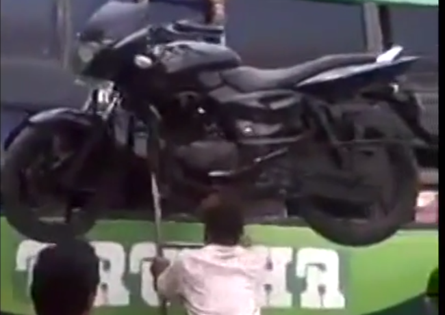 India: egy férfi a fején viszi fel a motort a busz tetejére - videó