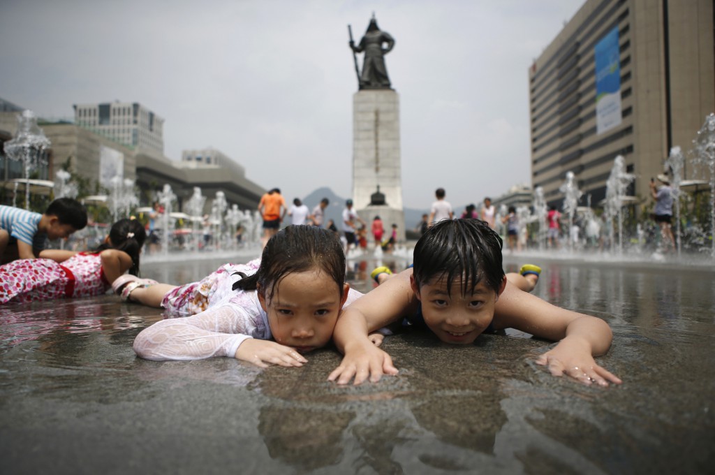 Children play in a fountain to cool down on a hot summer day in front of the General Lee Soon-shin statue in Gwanghwamun, Seoul