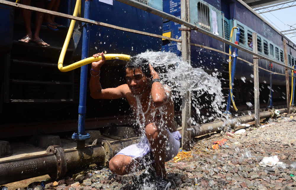 ALLAHABAD, INDIA - 2015/05/24: An Indian commuter uses the train water pipes  to bath  at railway station in Allahabad. Most of north India has been reeling under heat wave conditions with temperature soaring to over 46 degree Celsius (115 degrees Fahrenheit) . (Photo by Prabhat Kumar Verma/Pacific Press/LightRocket via Getty Images)
