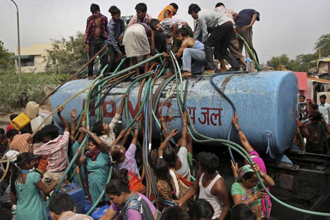 In this photo taken Friday, July 6, 2012, residents crowd around a government tanker delivering drinking water because of short supply in running water taps in New Delhi, India. Many areas of the Indian capital are facing acute water shortage, a repeated annual phenomenon during summer when taps go dry as demand rises. (AP Photo/Kevin Frayer)