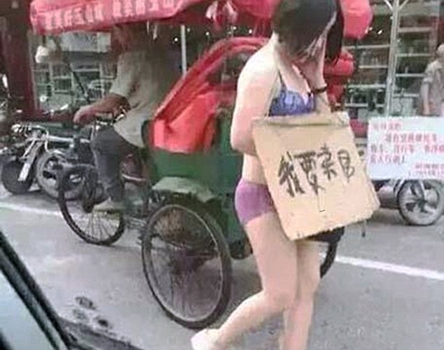 Pic shows: The woman walking on the street. A man has penned an official apology to his local newspaper for drunkenly beating his wife and forcing her to parade through the city streets half naked after deciding she had been unfaithful. Wang Ni, 33, was seen wearing only her underwear while walking through traffic in Yushan County of southeast China’s Jiangxi Province, and holding up a sign that read, "I want to sell my body". Wang had allegedly been beaten by her husband Zhang, 37, after which she was forced to parade through the streets half naked. The husband was reportedly following her in his car to make sure she continued on the walk of shame. The couple have two daughters but the husband works long hours and has little time for their relationship, and even lives in another city where he runs a property development company. According to friends of the couple, he blamed his wife for the fact that despite 10 years of marriage she had given him two daughters and no sons - causing frequent rows that had split the family and meant that he often abused his wife on the few occasions when he did return home. But that abuse reached a new high when he returned home for a rare visit and decided to go out drinking with his friends who spread rumours that Wang was cheating on him with another man. Upon hearing the rumours, the drunken Zhang charged home and after beating Wang, and accusing her of being unfaithful, stripped her and forced her onto the streets with the sign. After police officers rescued the unfortunate woman and took her back to the police station, they called Zhang in for questioning. The result of the questioning was proof that the young woman had not been unfaithful and that her husband simply listened to malicious rumours with no foundation. Zhang later apologised to Wang and penned a formal apology in his local newspaper. It is not clear whether his wife has accepted his apology. (ends)
