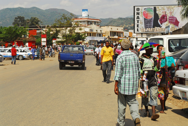 D4T2R5 Burundi, Bujumbura, vehicles with people on road with houses in background in city. (MR)