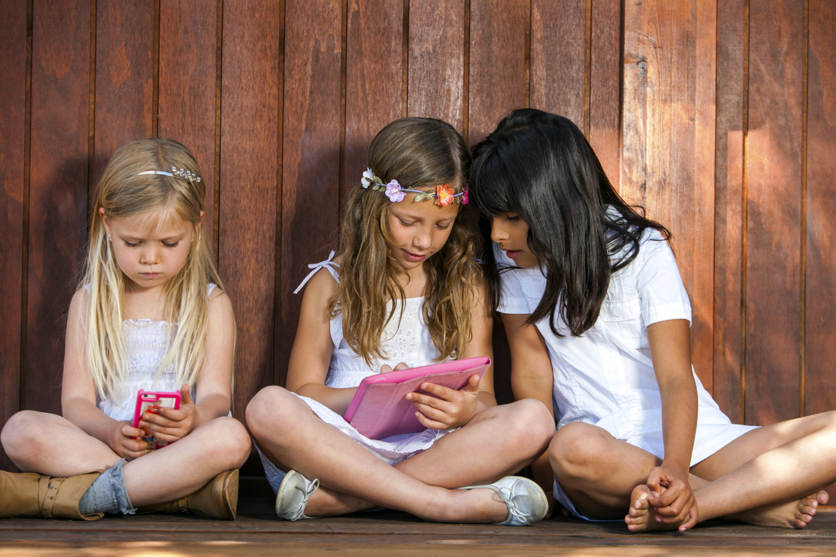Three girls playing with tablet and smart phone.