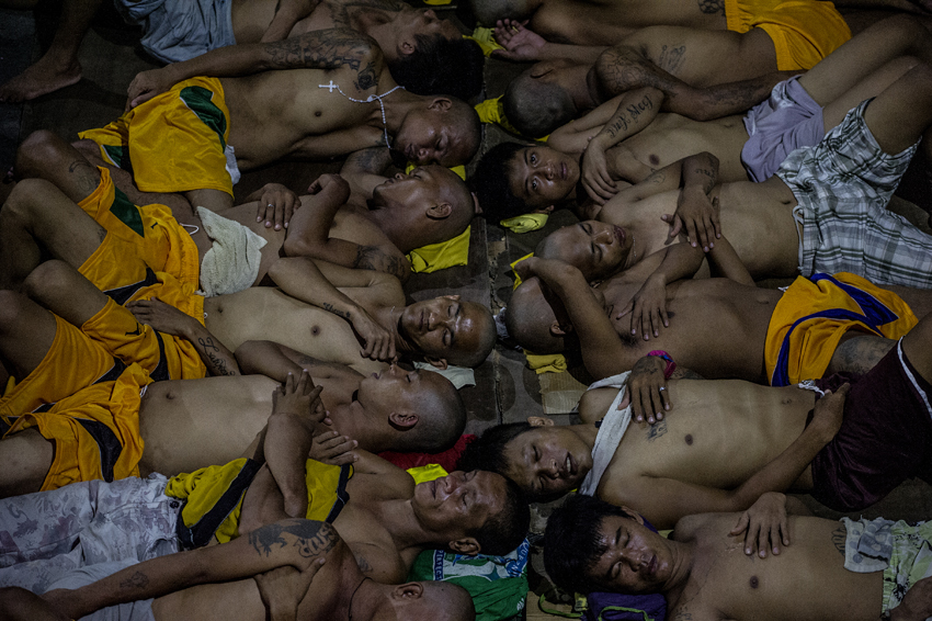 Inmates sleep on the ground of an open basketball court inside the Quezon City jail at night in Manila in this picture taken on July 19, 2016. There are 3,800 inmates at the jail, which was built six decades ago to house 800, and they engage in a relentless contest for space. Men take turns to sleep on the cracked cement floor of an open-air basketball court, the steps of staircases, underneath beds and hammocks made out of old blankets. / AFP PHOTO / NOEL CELIS / TO GO WITH AFP STORY: Philippines-politics-crime-jails, FOCUS by Ayee Macaraig