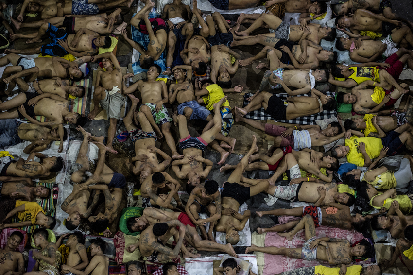 Inmates sleep on the ground of an open basketball court inside the Quezon City jail at night in Manila in this picture taken on July 19, 2016. There are 3,800 inmates at the jail, which was built six decades ago to house 800, and they engage in a relentless contest for space. Men take turns to sleep on the cracked cement floor of an open-air basketball court, the steps of staircases, underneath beds and hammocks made out of old blankets. / AFP PHOTO / NOEL CELIS / TO GO WITH AFP STORY: Philippines-politics-crime-jails, FOCUS by Ayee Macaraig