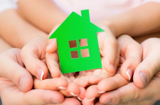 Family holding green paper house