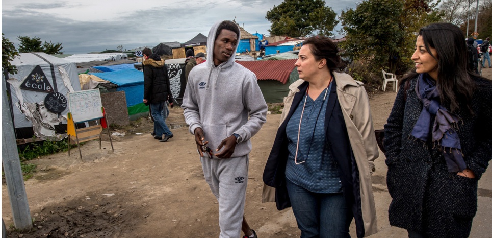 Europe Ecology - The Greens (EELV) National Secretary Emmanuelle Cosse (C) and EELV European MP Karima Delli (R) speak to a resident as they visit the "Jungle", a migrant and refugee camp, in Calais on October 30, 2015. AFP PHOTO / PHILIPPE HUGUEN / AFP PHOTO / PHILIPPE HUGUEN