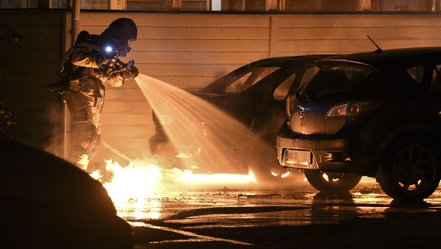 A firefighter works to extinguish a car fire at Persborgsgatan in Malmo, Sweden, Tuesday Sept. 20, 2016. Police in Malmo say a recent surge in car fires, with about 30 cars set ablaze since Friday, could be linked to a crackdown on gangland crime, after police arrested three men with suspected links to organised crime involving guns and explosives. (Johan Nilsson / TT via AP)